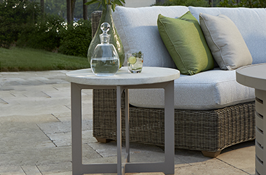 round side table beside a woven couch with gray and green cushions