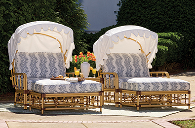 white cushioned lounge chairs with ottomans and shade cover on a green lawn