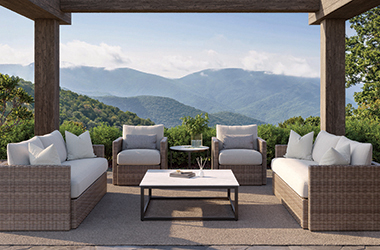 woven brown side table and sofa with cream cushions, blue blanket and pillows