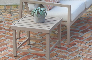 pale brown square side table beside a loveseat on a brick patio