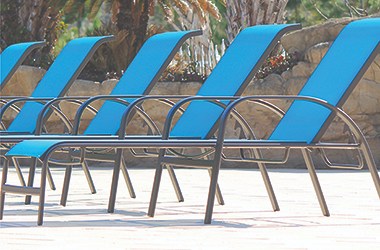 A row of blue reclined poolside chairs