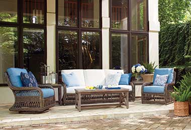 woven brown sofa and chairs with blue and white cushions