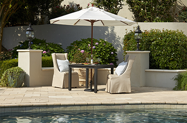 poolside table with white umbrella and tan chairs