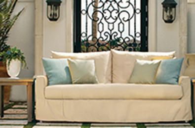 candlelit green sofa on a patio with wicker side table
