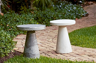 round stone white table in front of woven couch with light blue cushions