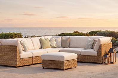 woven brown couch topped with white cushions beside a potted palm