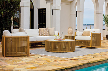 woven brown side table and sofa with cream cushions, blue blanket and pillows