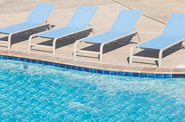 four blue reclined chairs by a pool