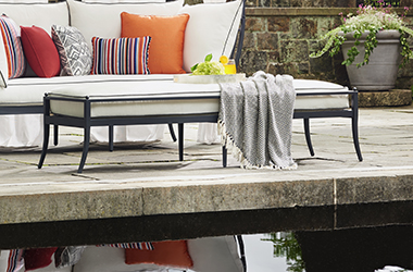 poolside white couch with orange and red pillows and a long ottoman