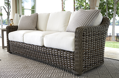 dark brown woven sofa with white cushions